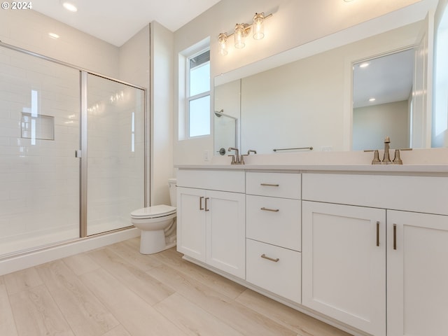 bathroom featuring hardwood / wood-style flooring, vanity, a shower with shower door, and toilet