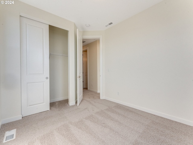 unfurnished bedroom featuring light carpet and a closet