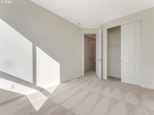 unfurnished bedroom with light colored carpet and a closet