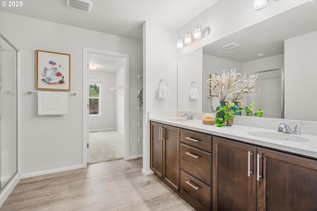 bathroom with hardwood / wood-style flooring, vanity, and a shower with shower door