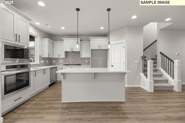 1353 NE Josephine Ct Unit 167, Estacada, OR 97023 - kitchen with a sink, stainless steel appliances, light wood-style floors, a kitchen island, and light countertops