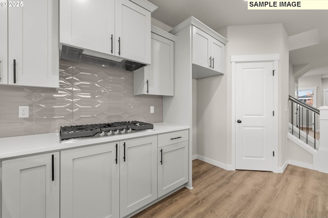 1353 NE Josephine Ct Unit 167, Estacada, OR 97023 - kitchen featuring tasteful backsplash, light wood-style flooring, stainless steel gas stovetop, light countertops, and under cabinet range hood
