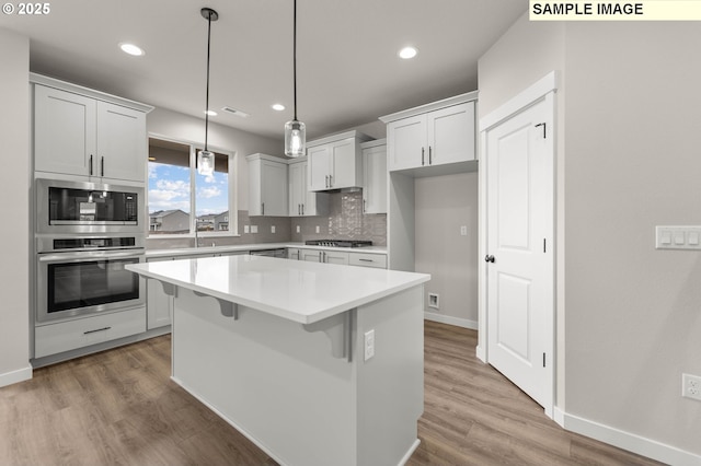 1353 NE Josephine Ct Unit 167, Estacada, OR 97023 - kitchen with decorative backsplash, stainless steel appliances, light countertops, light wood finished floors, and a center island
