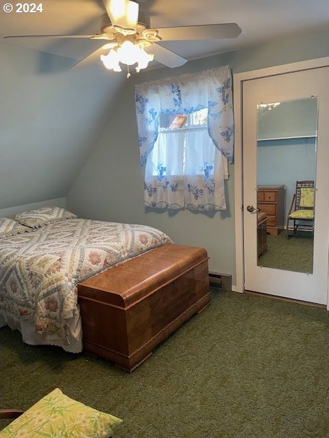 bedroom featuring dark colored carpet, vaulted ceiling, and ceiling fan