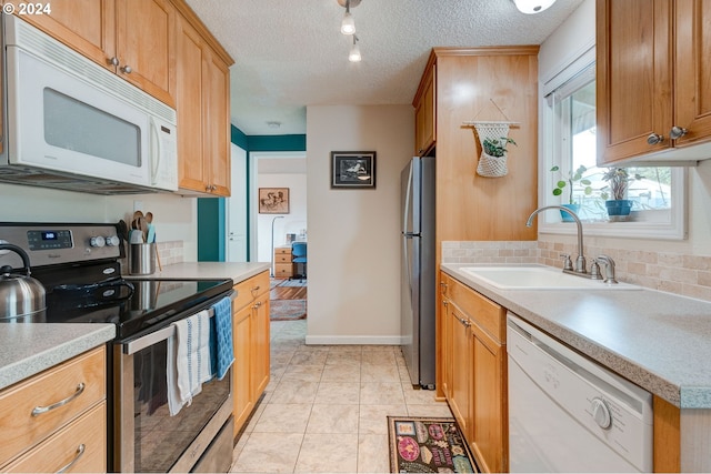 kitchen featuring appliances with stainless steel finishes, a textured ceiling, light tile patterned floors, and sink