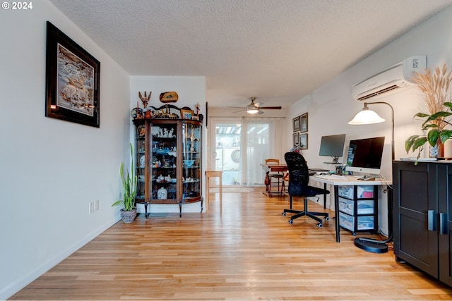 office area with a wall mounted AC, ceiling fan, light hardwood / wood-style flooring, and a textured ceiling