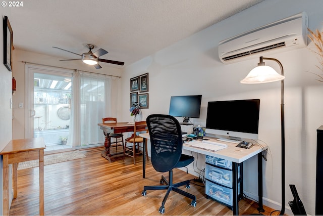 office with a wall mounted AC, ceiling fan, a textured ceiling, and light wood-type flooring