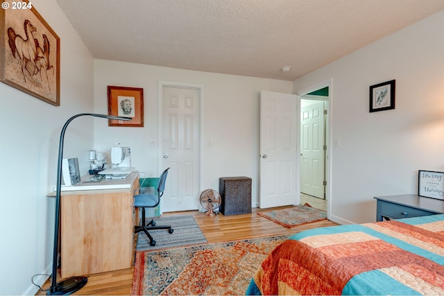 bedroom featuring light hardwood / wood-style floors and a textured ceiling