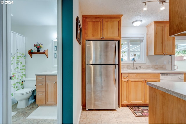 kitchen with sink, stainless steel fridge, white dishwasher, a textured ceiling, and light tile patterned flooring