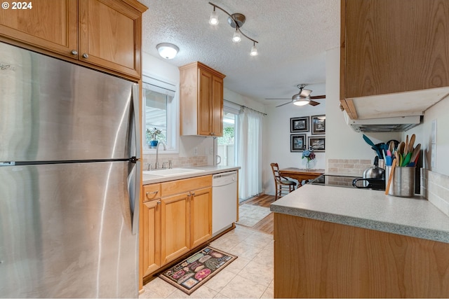 kitchen featuring dishwasher, sink, ceiling fan, a textured ceiling, and stainless steel refrigerator