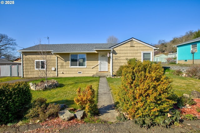 view of front of home with a front yard, roof with shingles, and fence