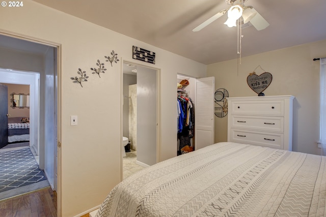 bedroom with a closet, a spacious closet, connected bathroom, ceiling fan, and light hardwood / wood-style flooring