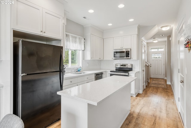 kitchen featuring decorative backsplash, light hardwood / wood-style flooring, stainless steel appliances, white cabinets, and a center island