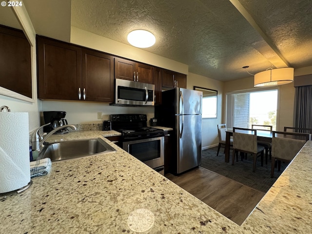 kitchen featuring dark brown cabinets, sink, a textured ceiling, dark hardwood / wood-style floors, and stainless steel appliances