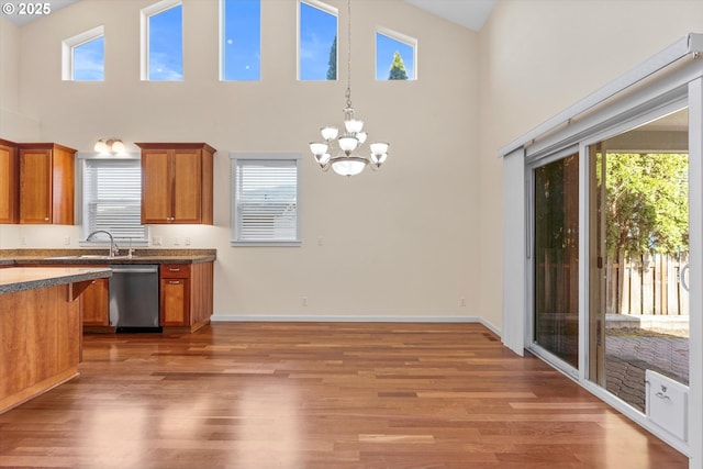 kitchen featuring stainless steel dishwasher, brown cabinetry, light wood-style floors, and a healthy amount of sunlight