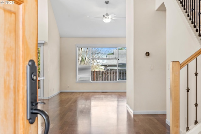 foyer entrance with vaulted ceiling, stairway, a ceiling fan, and wood finished floors