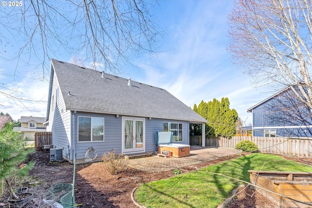 rear view of property with french doors, fence, a shingled roof, and a hot tub