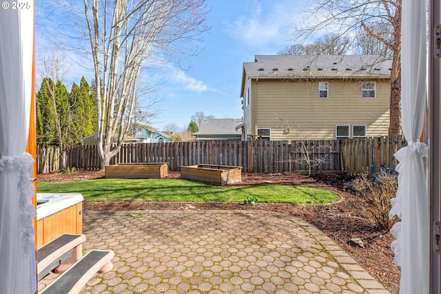 view of yard with a garden, a hot tub, a fenced backyard, and a patio area