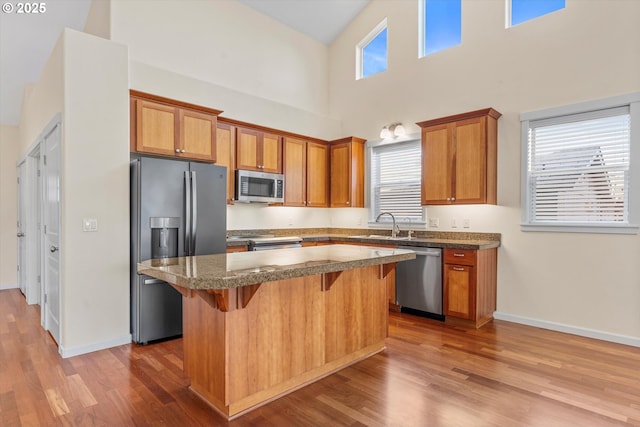 kitchen with a kitchen island, appliances with stainless steel finishes, a breakfast bar, and a healthy amount of sunlight