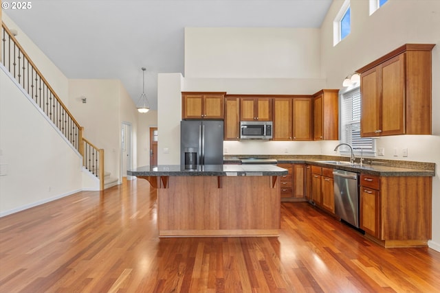 kitchen with wood finished floors, brown cabinetry, a kitchen island, and stainless steel appliances