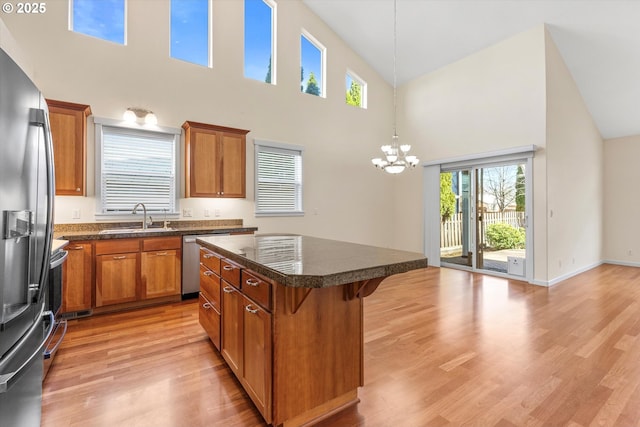 kitchen featuring light wood finished floors, brown cabinetry, appliances with stainless steel finishes, and a sink