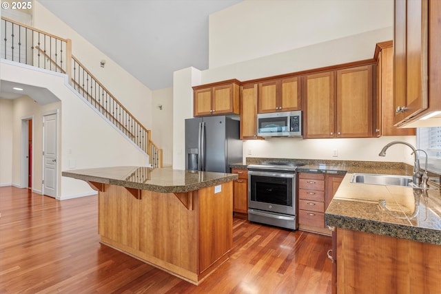 kitchen featuring dark wood finished floors, brown cabinetry, appliances with stainless steel finishes, and a sink