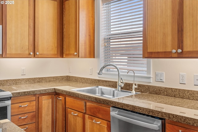 kitchen with a sink, tile countertops, brown cabinetry, and stainless steel appliances