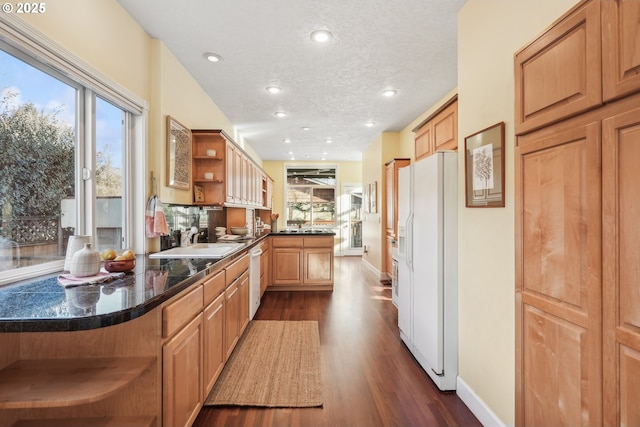 kitchen featuring sink, dark hardwood / wood-style floors, white refrigerator with ice dispenser, and kitchen peninsula