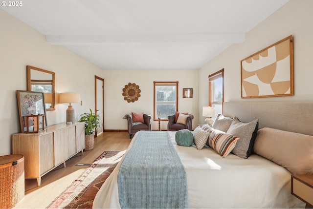 bedroom with light wood-type flooring and beamed ceiling