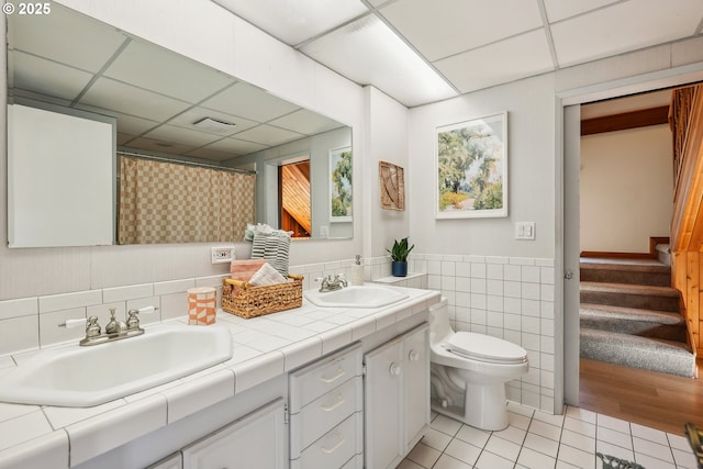 bathroom featuring toilet, vanity, tile patterned flooring, and a drop ceiling