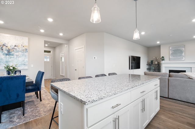 kitchen with decorative light fixtures, a kitchen breakfast bar, white cabinets, and a center island