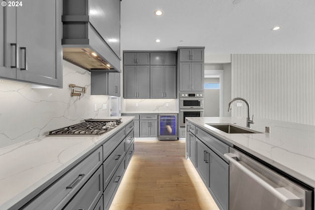 kitchen featuring custom exhaust hood, sink, gray cabinets, and stainless steel appliances