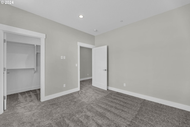 unfurnished bedroom featuring a closet, a spacious closet, and carpet floors