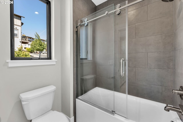 bathroom with toilet and bath / shower combo with glass door