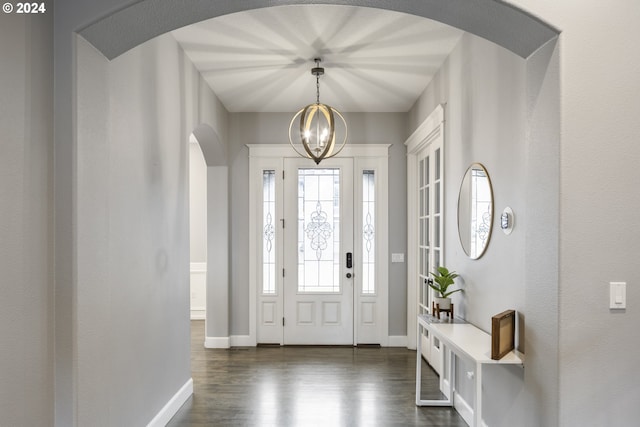 foyer entrance with dark hardwood / wood-style floors and an inviting chandelier