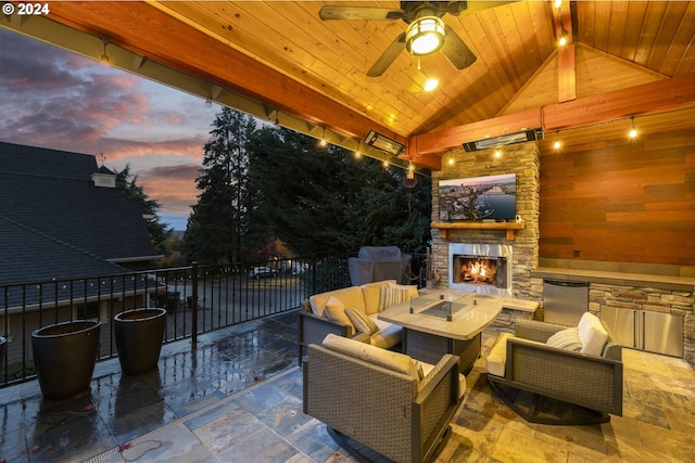 patio terrace at dusk with an outdoor living space with a fireplace and ceiling fan