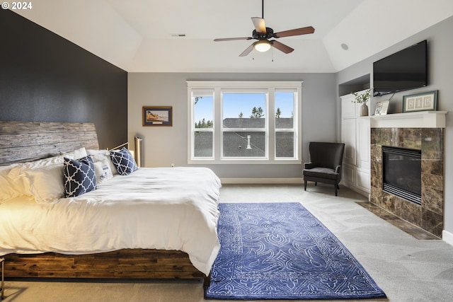 bedroom with light carpet, a tile fireplace, vaulted ceiling, and ceiling fan