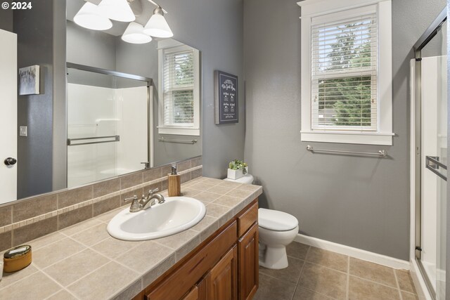 bathroom with tasteful backsplash, tile patterned floors, walk in shower, vanity, and a chandelier