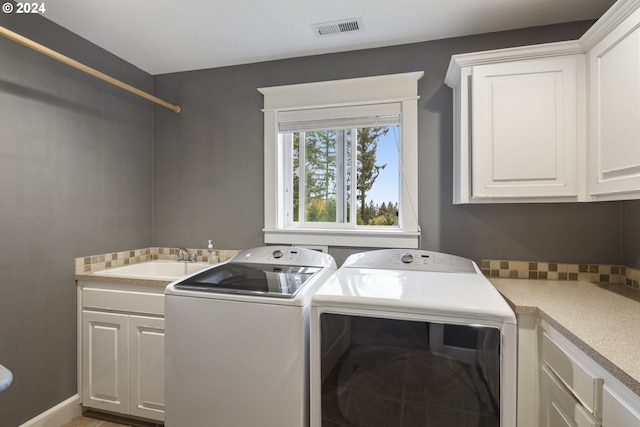 laundry area featuring cabinets, washer and clothes dryer, and sink