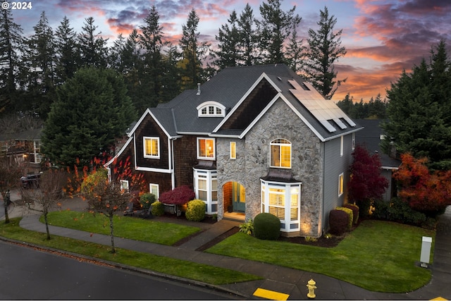 view of front of home with solar panels and a yard