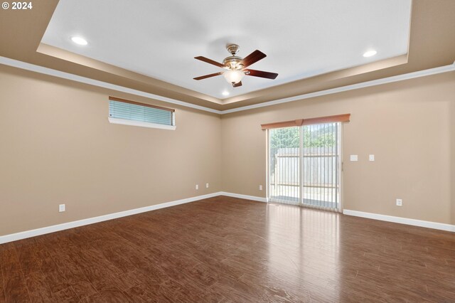 empty room featuring ceiling fan, dark hardwood / wood-style flooring, and a tray ceiling