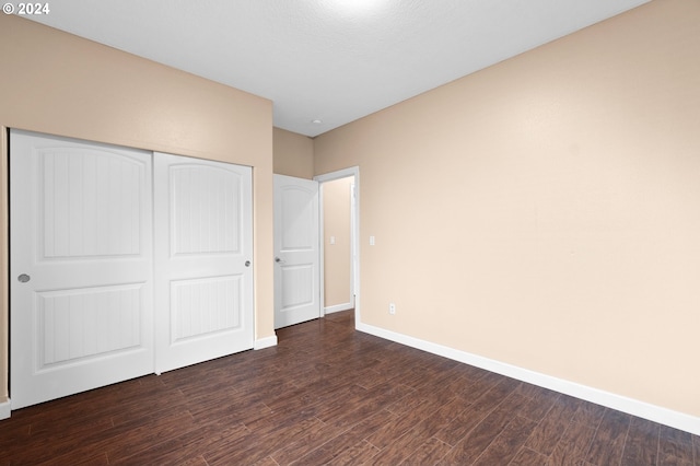 unfurnished bedroom featuring dark wood-type flooring and a closet