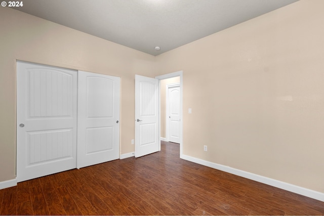 unfurnished bedroom with dark hardwood / wood-style flooring and a closet