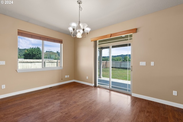 spare room featuring hardwood / wood-style flooring, a chandelier, and a wealth of natural light