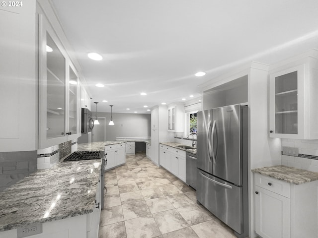 kitchen with tasteful backsplash, decorative light fixtures, white cabinetry, and appliances with stainless steel finishes