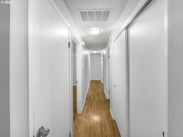 hall featuring light hardwood / wood-style flooring and a textured ceiling