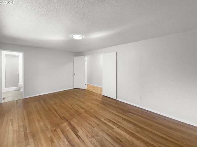 unfurnished room with wood-type flooring and a textured ceiling