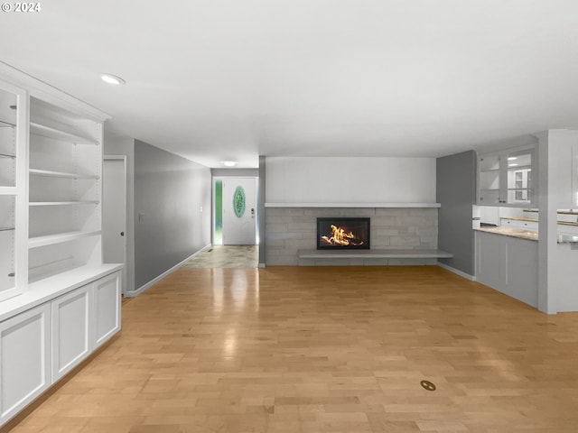 unfurnished living room featuring light hardwood / wood-style flooring and a tile fireplace