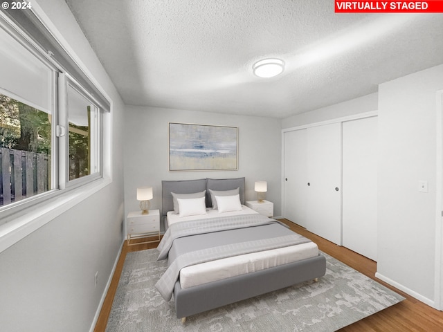 bedroom with a closet, a textured ceiling, and hardwood / wood-style flooring