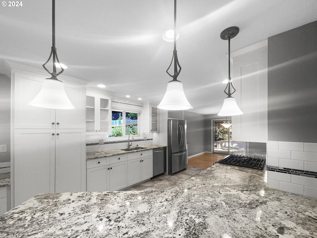 kitchen with light stone countertops, decorative light fixtures, sink, white cabinets, and appliances with stainless steel finishes